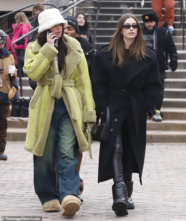 Glamor friend: With her brunette locks down and straight, Hailey walked past a friend who was dressed to the nines in a chartreuse coat and fluffy white bucket hat