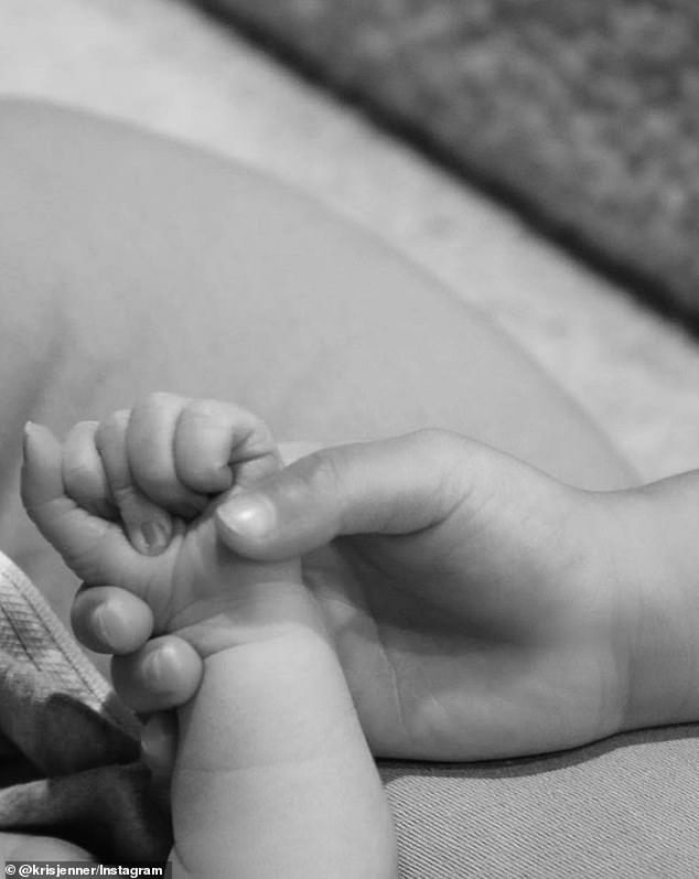 Holding hands: Kris put her fingers in the hand of a tiny baby, possibly one of her most recent grandchildren.