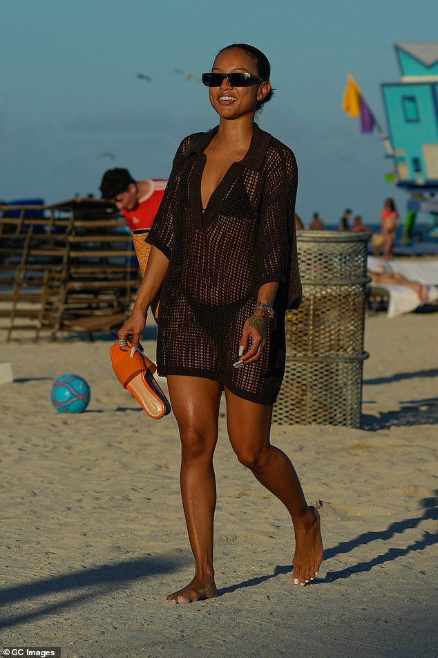 Knit Top: While walking along the shoreline, Tran wore a black knit top that showed off her perky butt.