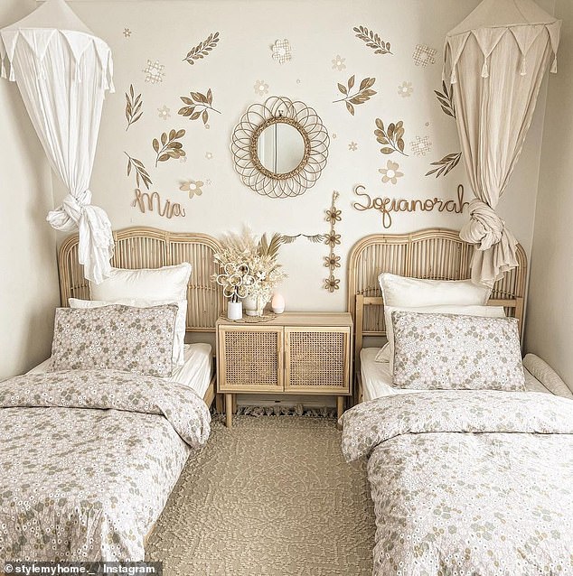 His daughters' quaint shared bedroom features twin beds with mosquito nets, wall stickers, custom wicker signs, bedding by Harris Scarf, and a wicker table from Kmart.