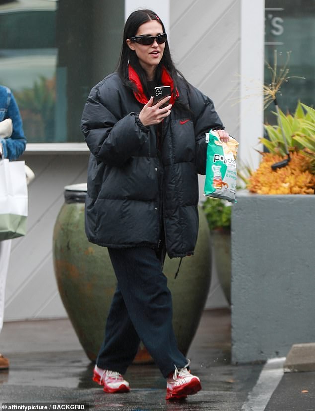 Sheltered: The 21-year-old model stepped out in an oversized black puffy jacket with red trim in the gray and rainy weather