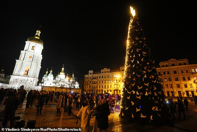 Ukrainians celebrate New Year's Eve before the start of the curfew, near a Christmas tree decorated in the colors of the Ukrainian flag on Sofia Square in Kyiv, Ukraine, on December 31, 2022.