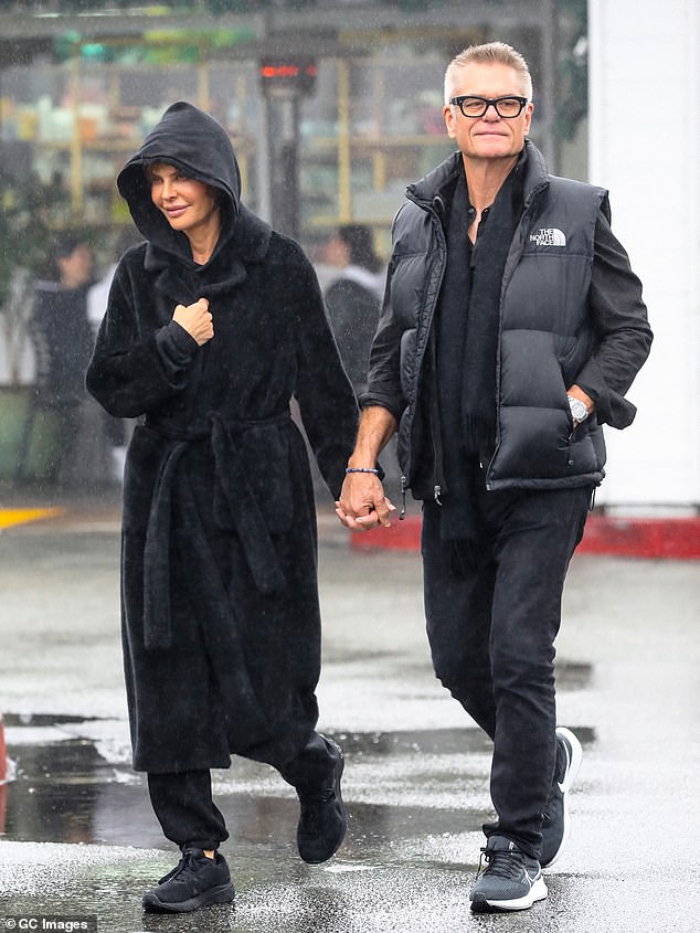 Rainy day chic: The Real Housewives of Beverly Hills star kept dry in a black hoodie, over which she wore a long black coat