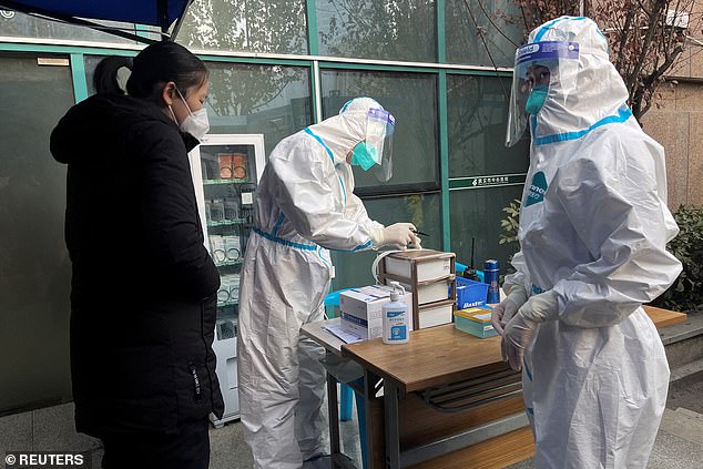 A medical worker in a protective suit records information for a patient at the entrance of the fever clinic of Wuhan Central Hospital, amid the coronavirus disease (COVID-19) outbreak, in Wuhan, Hubei province, China, 31 December 2022