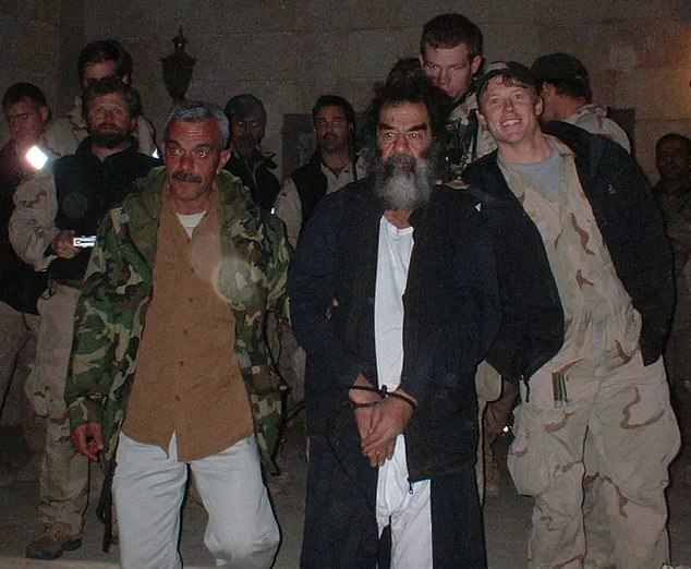 Holland, seen on the far left in the December 2003 photo, revealed how he and his brother's arms came to find the eight-foot-deep hole, and how they found an emaciated Hussein armed with a pistol in the hole. inside.