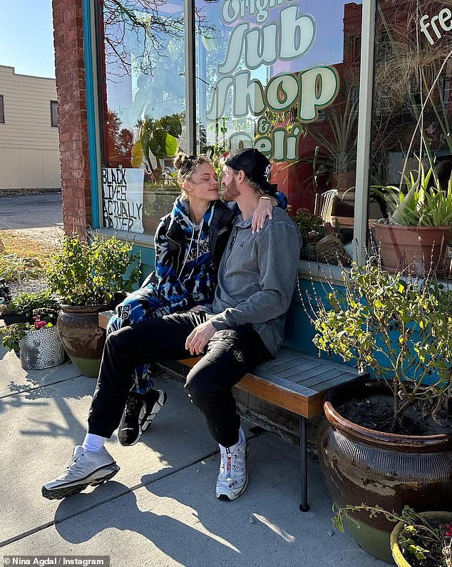 Leaning in: The couple leaned in for a kiss on a bench outside a sandwich shop