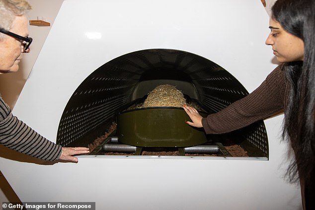 Two people look at a shrouded mannequin inside a boat, where the bodies often lie for a month as they decompose before turning into mulch.