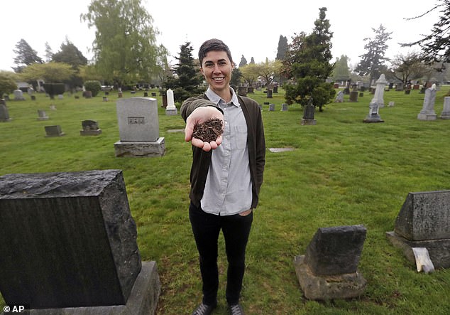 Katrina Spade, founder and CEO of Recompose, shows a sample of compost material left over from a cow's decomposition, using a combination of wood chips, alfalfa and straw, as she poses in a Seattle cemetery.