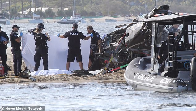 Police officers are shown holding a white sheet to protect a victim of the helicopter crash.