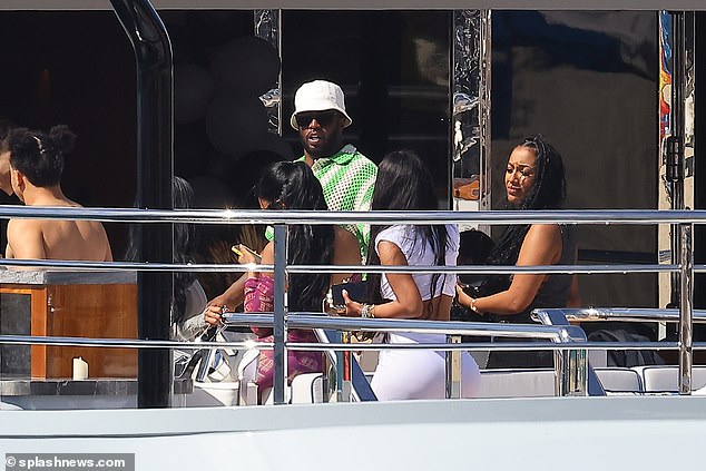 Looking good: The rapper, 53, looked casual in a white chiffon polo shirt with green stripes while accessorizing with a white bucket hat