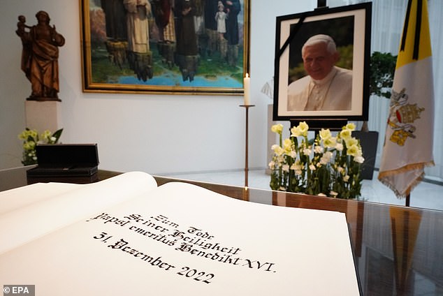 A portrait of the late former Pope wearing a black mourning ribbon on display alongside a condolence book at the Apostolic Nunciature in Berlin.