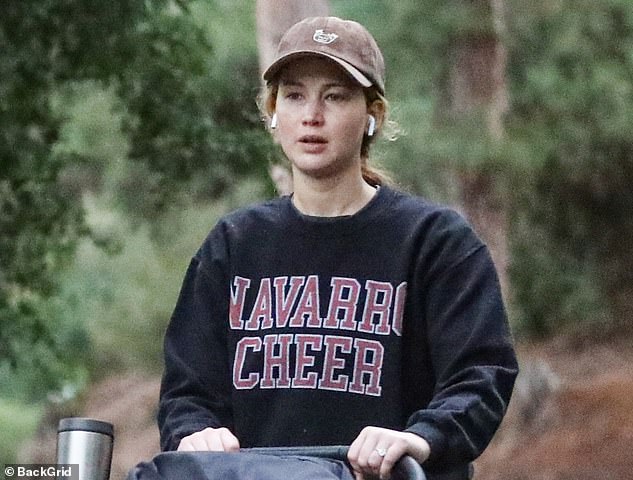 Cheer fan: With AirPods in each ear, the Hunger Games star wore a brown cap and a black hoodie that read 'NAVARRO CHEER'