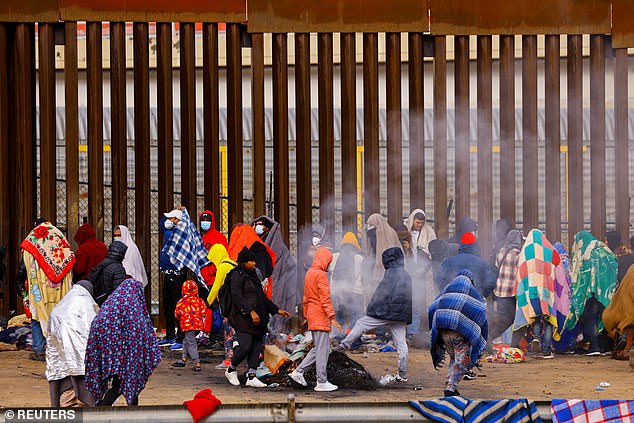 Migrants queue near the border fence after crossing the Rio Grande to request asylum in El Paso, Texas, on Monday.