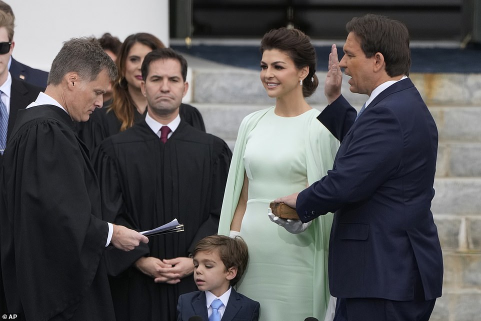 Casey holds a bible as her husband takes office with little Mason standing in front of her