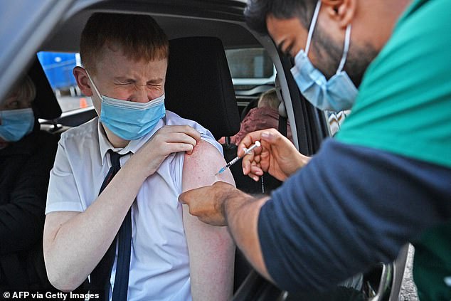 The essay itself , published on December 5, backs up evidence that jabs offer little benefit to preventing severe illness in younger people, who face a tiny threat from the virus itself. Pictured, a youngster getting a vaccine at a drive-through centre in Blackburn