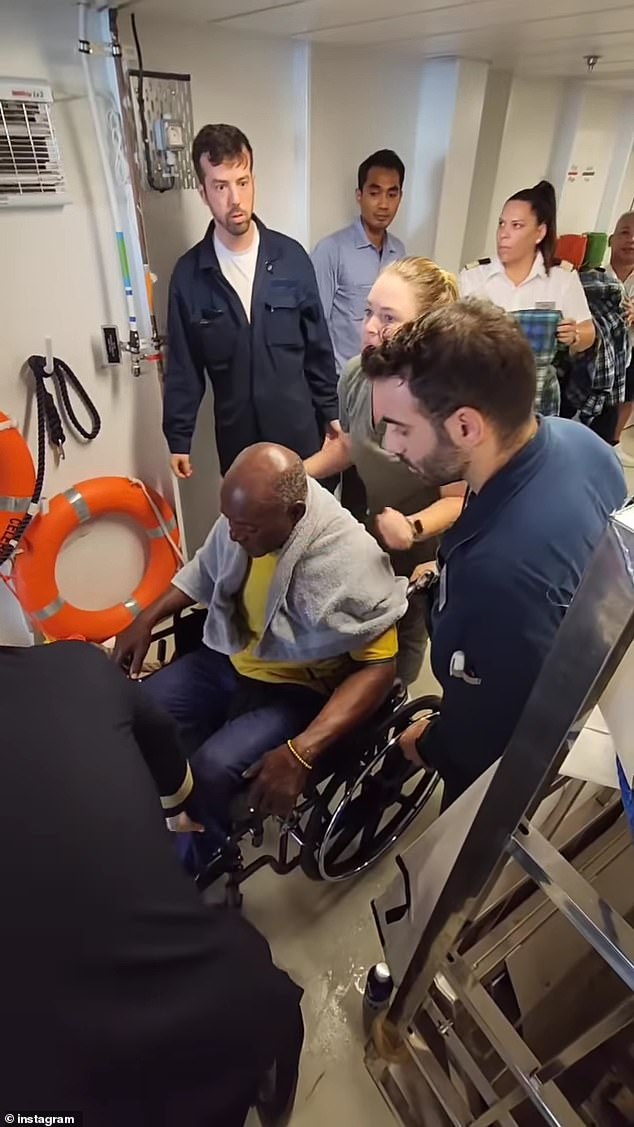 One of 19 migrants rescued from a wooden ship is helped into a wheelchair by crew members from a Celebrity Cruises ship on Monday.