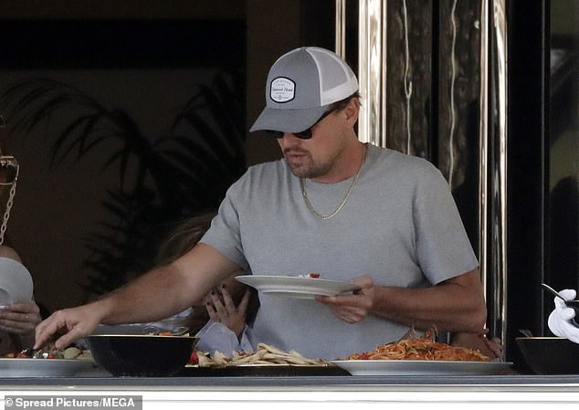 Casual cool: Leonardo himself was dressed in a simple gray T-shirt with a baseball cap and a pair of sunglasses as he relaxed on the deck of the ship