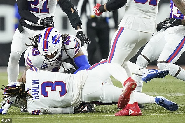 Buffalo Bills safety Damar Hamlin (3) lies on the grass after making a tackle on Cincinnati Bengals wide receiver Tee Higgins, who is blocked from view, as Buffalo Bills linebacker Tremaine Edmunds (49), assists at the end of the play during the first half.  of an NFL football game between the Cincinnati Bengals and the Buffalo Bills on Monday.  After getting up from the play, Hamlin collapsed and was administered CPR on the field.