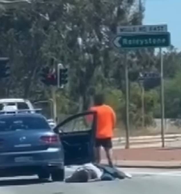 The man was left injured and lying on the road (pictured) as his attacker casually walked back to his white Toyota utility vehicle.