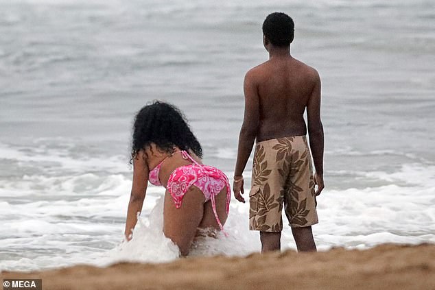 Relaxation: SZA laughed and smiled as she frolicked in the water with the mysterious buff man, even enjoying dancing near the edge of the waves.