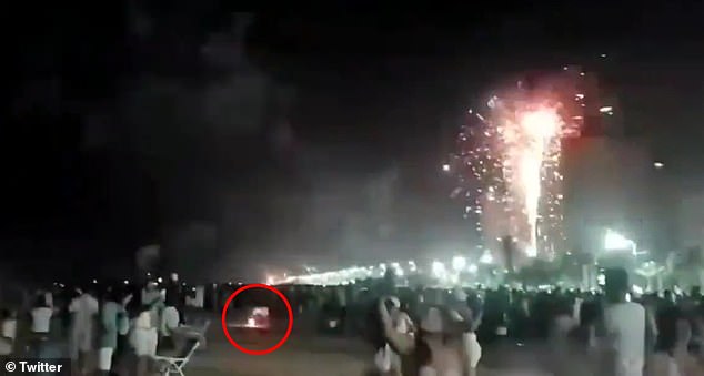 A man kneels in the sand and sets off fireworks before the explosive struck and killed a 38-year-old mother celebrating the new year on a Brazilian beach shortly after midnight on Sunday.