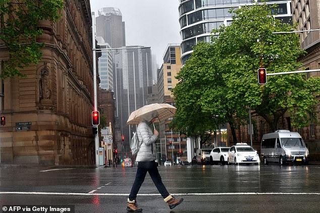 A moist, unstable air mass unleashed severe thunderstorms on Wednesday afternoon in parts of New South Wales.  Pictured is a woman sheltering from the rain under an umbrella as she crosses a street in Sydney.