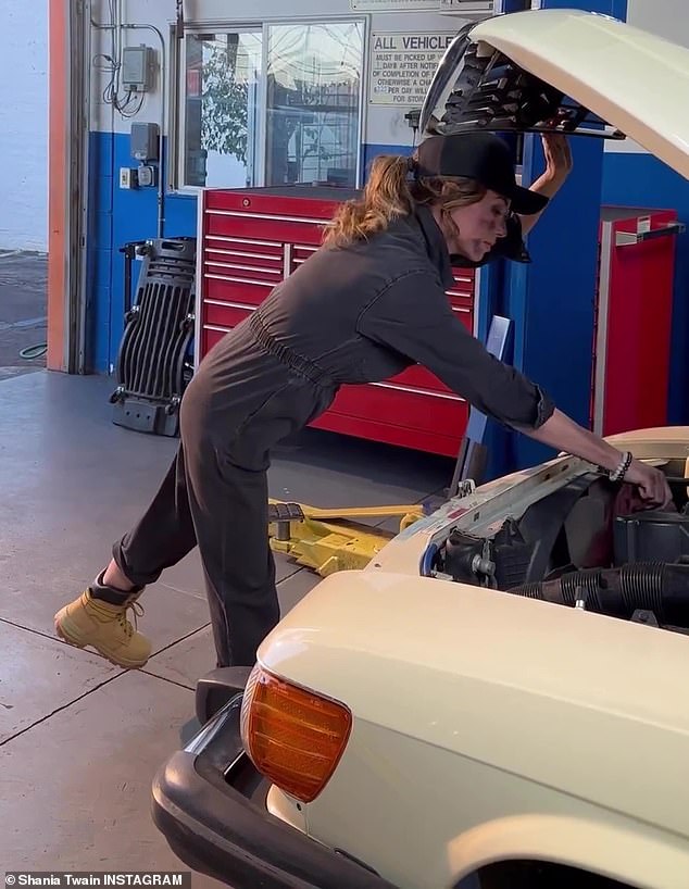 Showing off: The 57-year-old country icon covered her enviably slender body in a dark jumpsuit as she played mechanic, leaning over the open hood of a vintage car.