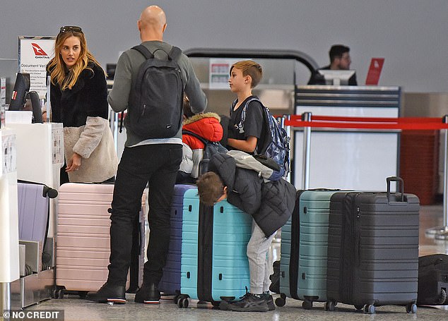 The AFL WAG looked like any other tourist as she argued with her children, including Oscar, Billie, Tom and Darcy, in the check-in line at Sydney airport.