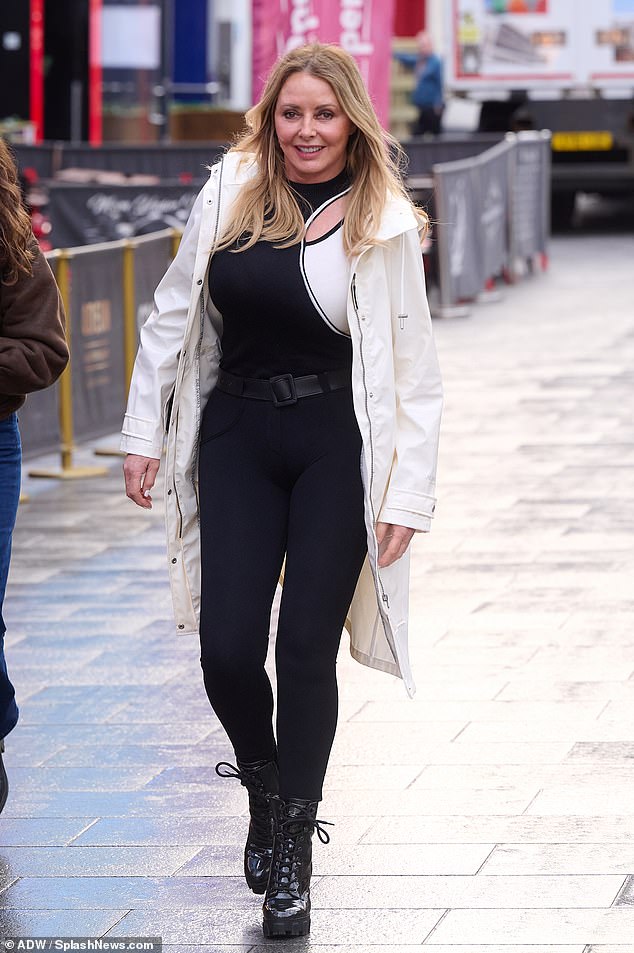 Looking good: The math genius showed off her ageless figure in a skintight black jumpsuit as she stepped out of the studio and into a white raincoat