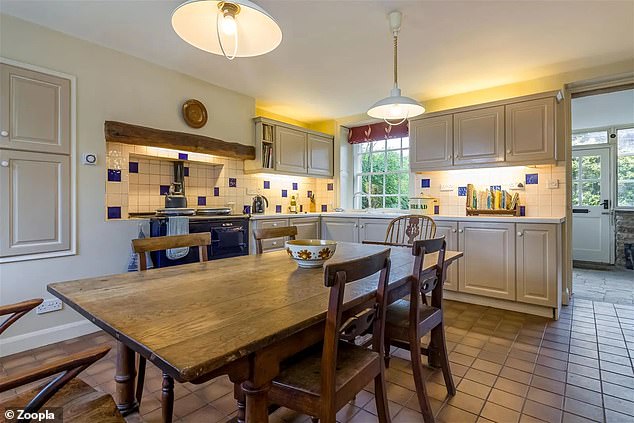 The kitchen has stone-colored wall and base cabinets and a rustic tiled floor