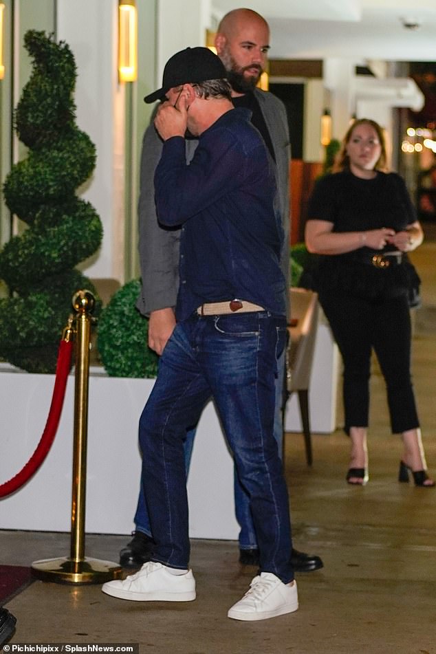 Party time: Leo donned dark jean pants with a cream belt, added a black button down, and a baseball cap.