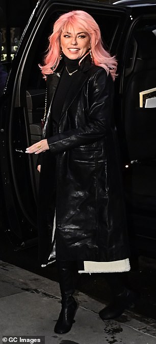 Elegant: She layered the coat over a sleek black turtleneck with a dangling gold chain that rested on her neckline.