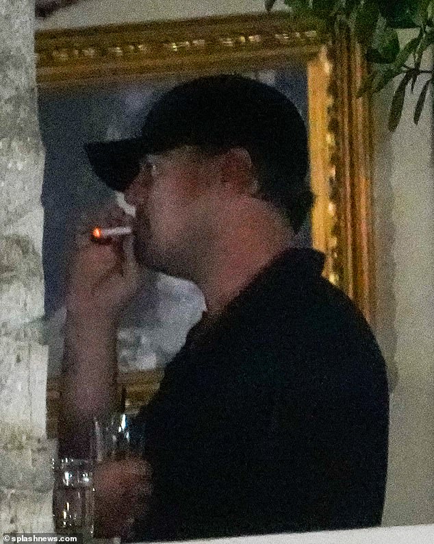 Holy fumes!  Leo was seen smoking a cigarette and enjoying a glass of wine at the party.