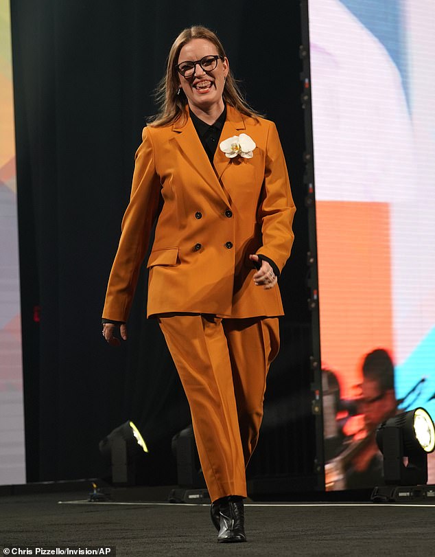 Stylish: The Canadian beauty was stylish in a mustard-toned two-piece suit featuring a double-breasted jacket with a simple brown button-down shirt underneath, brown boots and a white flowered boutonniere