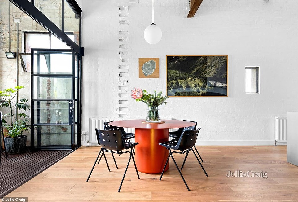 Soaring, angled ceilings make the open-plan kitchen and lounge airy and spacious, while natural light pours in through expansive full-height windows.