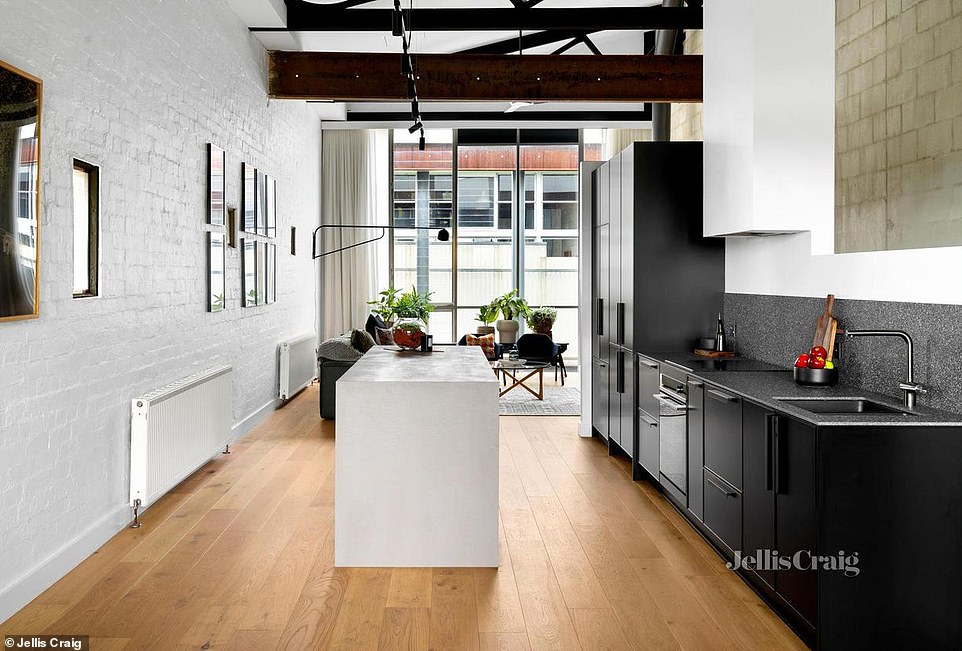 A sleek black kitchen features terrazzo countertops and a stone island bench, while a glass fireplace warms the living room