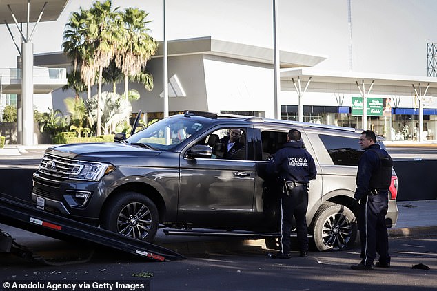 Police examine abandoned civilian vehicle during operation to capture Ovidio Guzmán