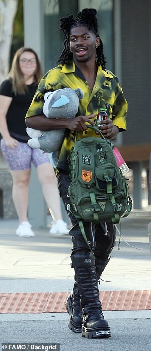 Lil Nas X was all smiles as he chatted with a friend, carrying a drink in one hand and a large green backpack in the other.