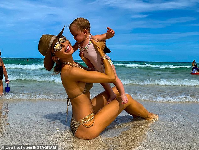 Smiling through the heartbreak: Tanned and made up to the nines, the latest flashback images of the reality star captured her holding the couple's baby girl, Elle, now three, on the beach  