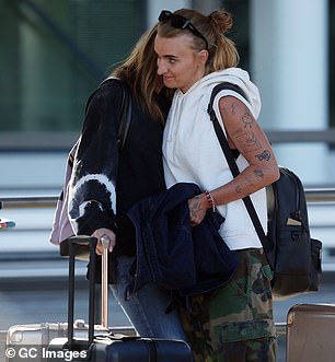 The lovebirds carried backpacks as they stood among several suitcases waiting for their transport.