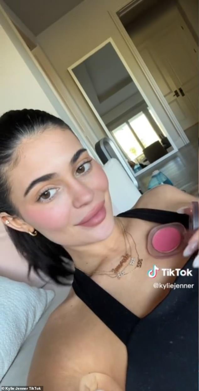 Her brand: The lip kit mogul had her dark hair pulled back into a ponytail and wore a black tank top while promoting her brand Kylie Cosmetics' luminous balm products.