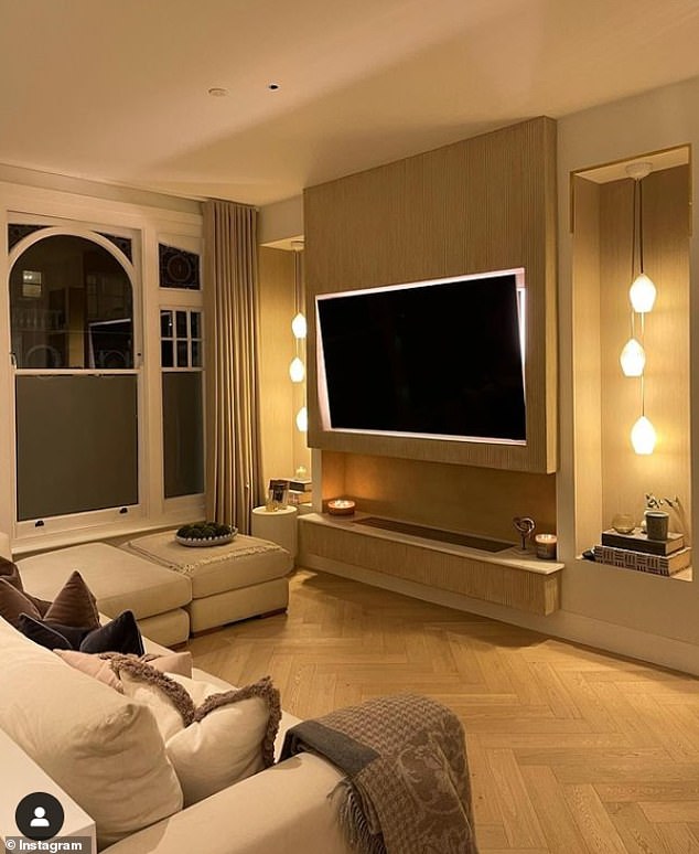 Cozy: The couple's flat-screen TV hangs on a wooden board with lights on either side