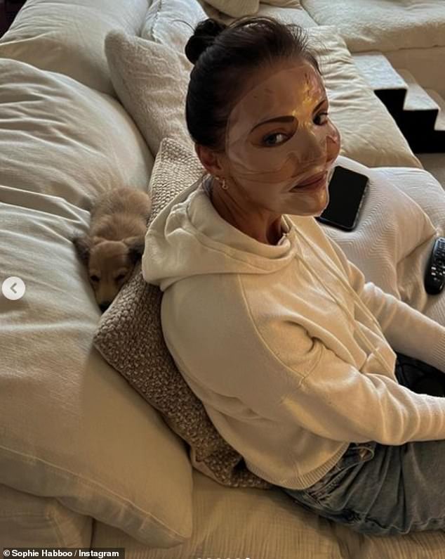 Relaxing: Sarah also sat on the couch wearing a face mask while Bobbie lay down behind her on Saturday