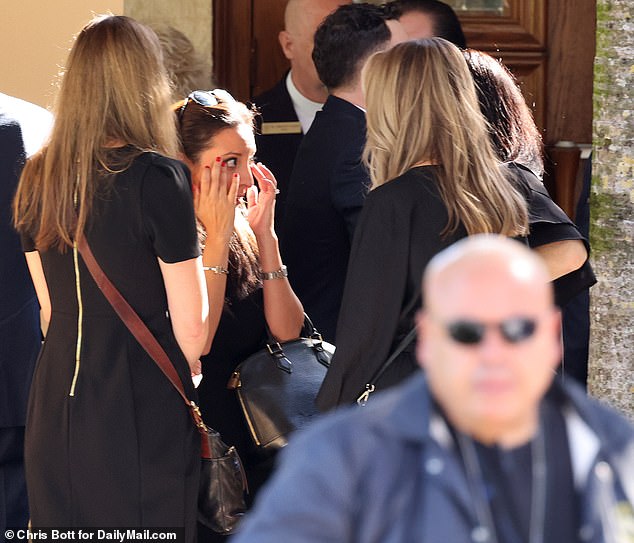 Veronica wipes away tears after family and friends comfort her at her husband's funeral