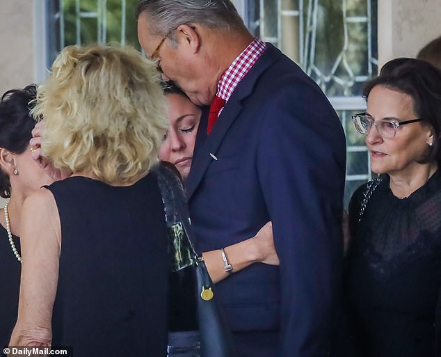 Verónica Tejera holds on to a loved one as she watches as her husband's coffin is placed in a hearse