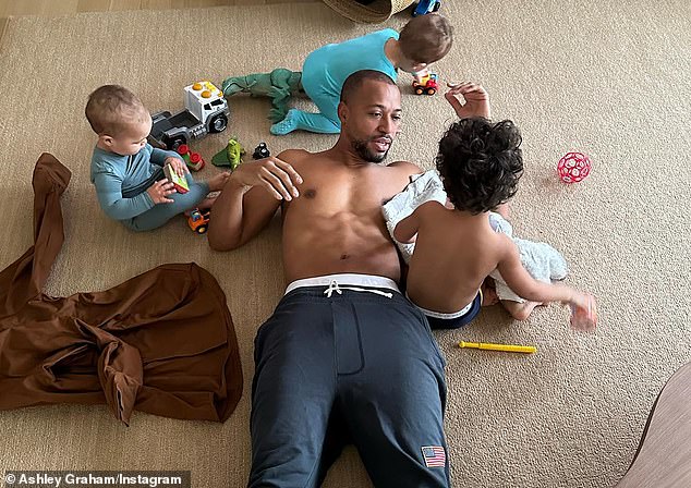 Nice daddy body: Ashley shares her twins, along with her older brother Isaac, who turns three this month, with her husband, cinematographer Justin Ervin, 35  Graham posted a shirtless photo of her handsome husband earlier this week, capturing Justin.  on the floor playing with his children