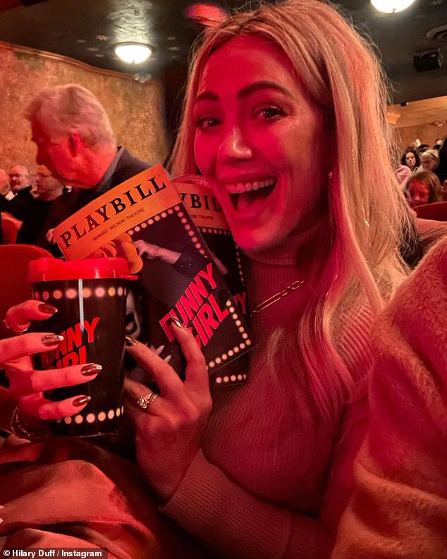 Funny girl fan girl: Once inside the theater, Duff posed excitedly while holding the Funny Girl Playbill sign and a matching reusable cup.