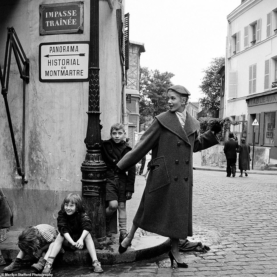 A model is seen with children on the street in Montmartre, Paris, circa 1955.