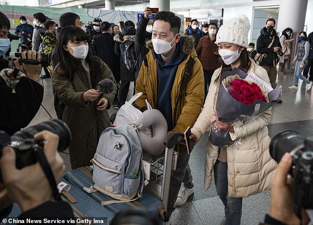 A man greets his girlfriend at the international arrivals hall of Beijing Capital International Airport as China lifts quarantine requirements for international arrivals