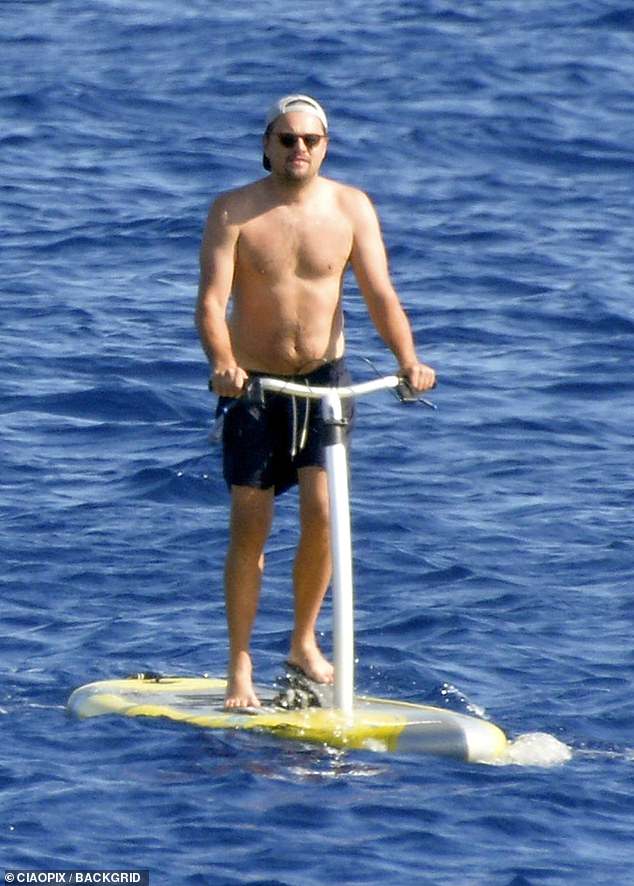 Trip: his jet-ski complete, Leonardo hopped on a pedal board and drove around the water while Camila surfed